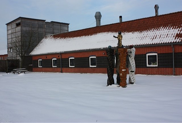 Tommerup Keramisk Værksted set fra forsiden med skulptur af Bjørn Nørgaard i forgrunden og bygning med højovn i baggrunden. Foto: Trine Rytter Andersen