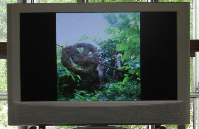 I Københavns urskov nedlægges et hakkekødfyldt Happy Face. Morten Plesner og Mikkel Horne Bervild, <i>5kg urinstinkt i hakket kalv og flæsk</i>, 2008. Foto: Kasper Lie.