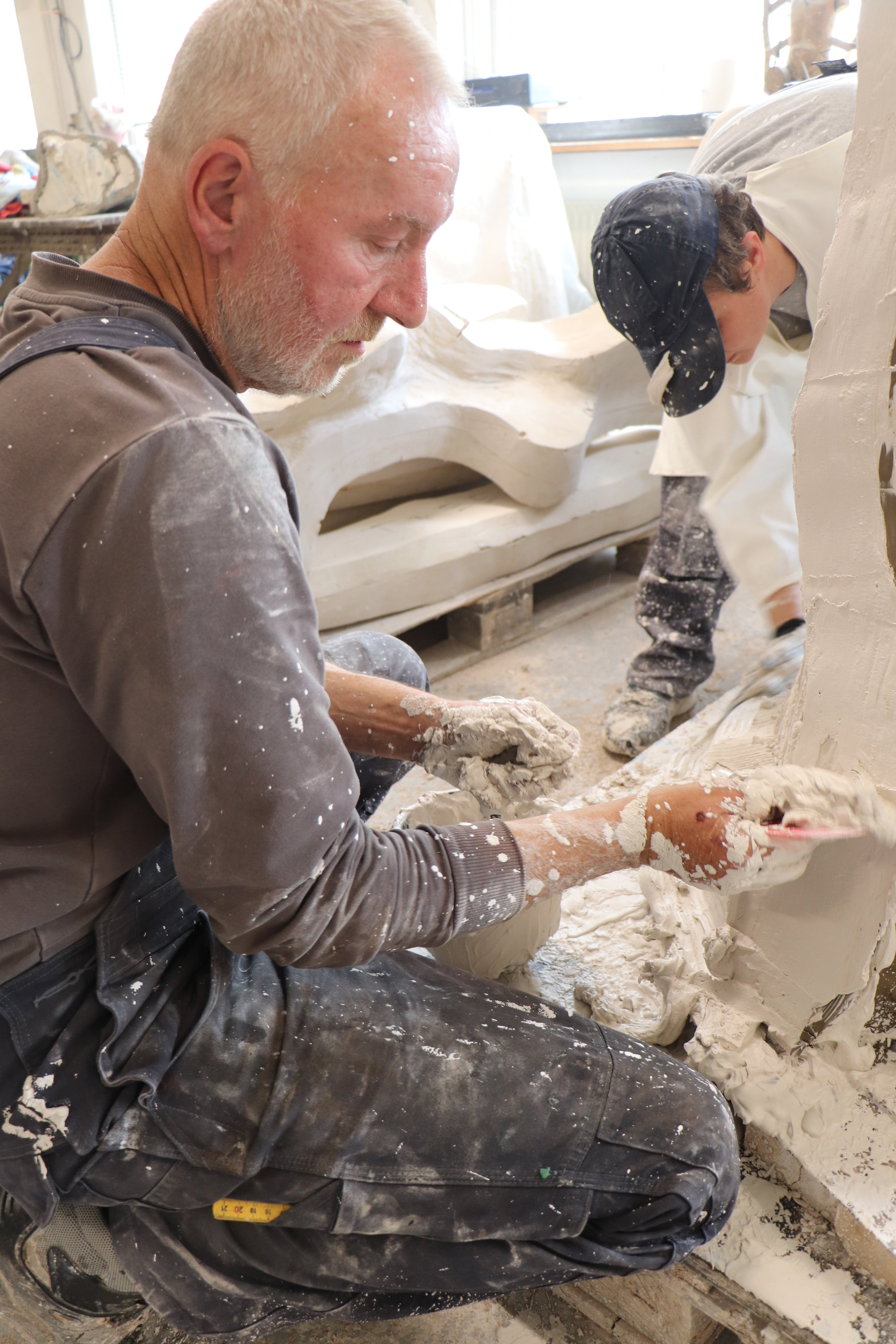Bronzestøber Peter Jensen (i forgrunden) og figurformer Orsolya File udfører en gipskappe omkring en silikoneform, der senere benyttes til at lave voksfigur i. Foto: Broncestøberiet Peter Jensen ApS.