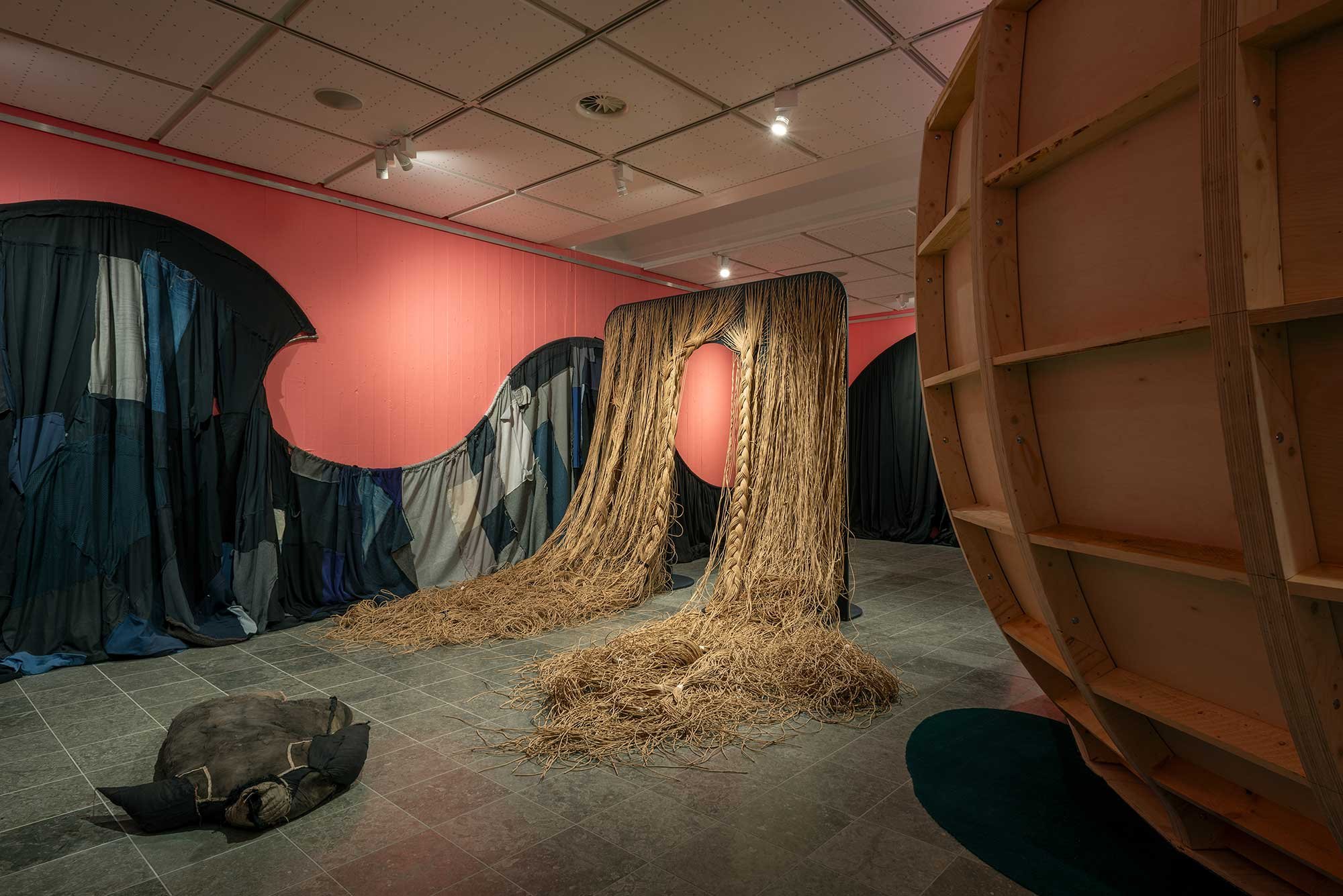 I udstillingsrummet mødes man af en indgangsportal, hvorfra kaskader af papirgarn vokser og flyder ud over gulvet. Det minder om overdimensioneret hår, og man ledes ind under ”pandehåret” og gennem portalen videre ind i udstillingen. Foto: Jacob Friis-Holm Nielsen
