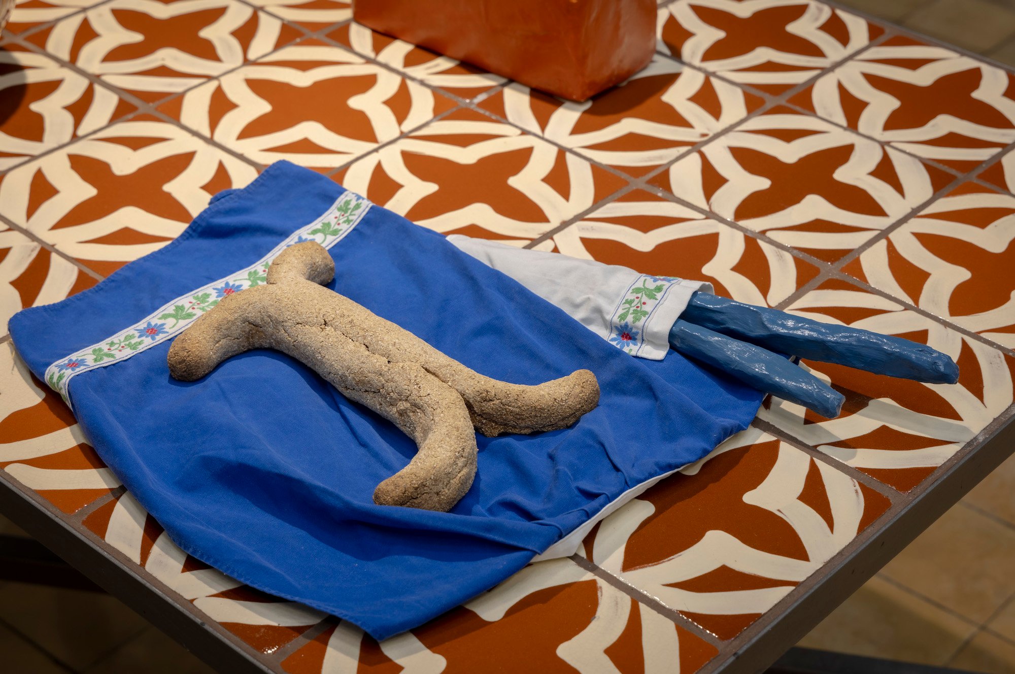 Milena Bonifacini, kakkelbord. forklæde, saltbagt brød, papier-mache, 2020-24, Det Fynske Kunstakademi Odense. Foto: Malle Madsen