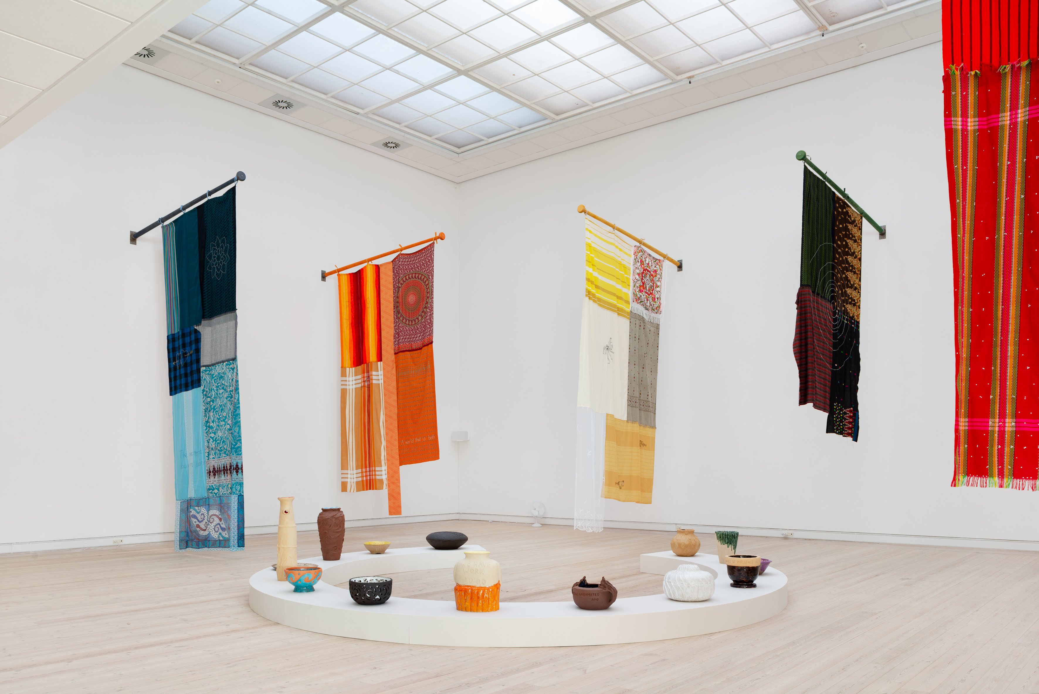 Hesselholdt og Mejlvang: 'Flag-installationen'<em> A world that is both under water and on fire</em>, 2025 og cirklen med stentøj på gulvet. Foto:  Jacob Friis-Holm Nielsen.