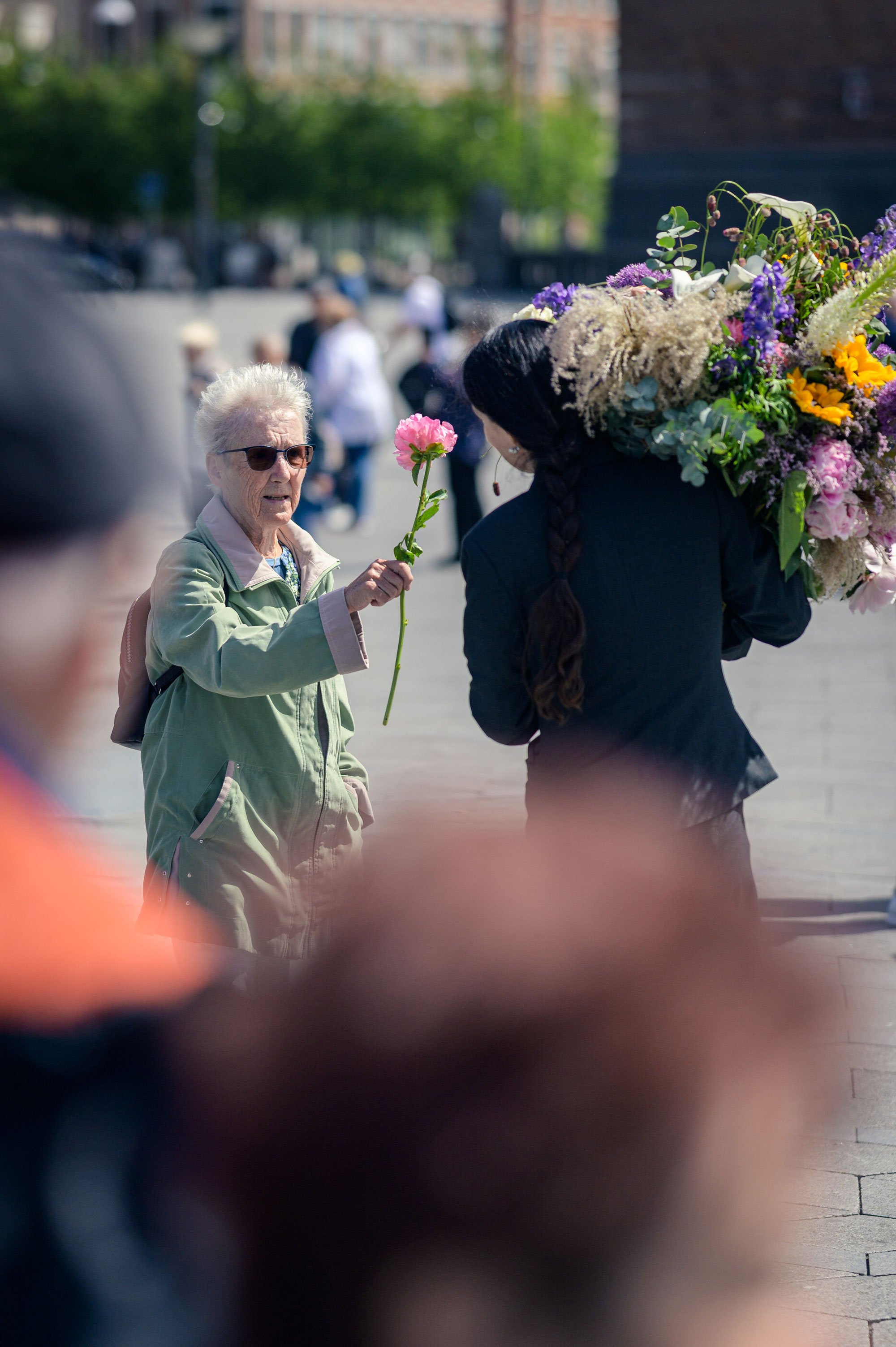 Kunstneren taber en enkelt blomst og de forbipasserende samler dem måske op - et glædeligt møde i menneskemylderet. Foto: Simon Skipper