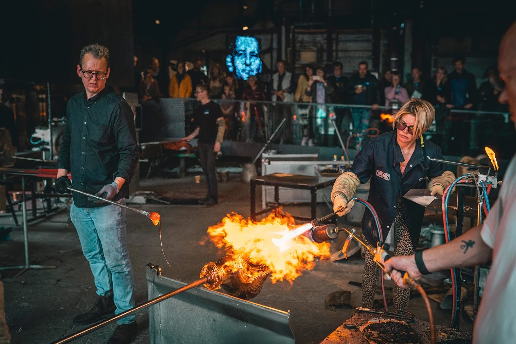Maria Koshenkova sammen med Bjørn Friborg and Peer Sonny, begge glaspustere på Holmegaard Værk. Foto: Mads Tolstrup / Museum Sydøstdanmark
