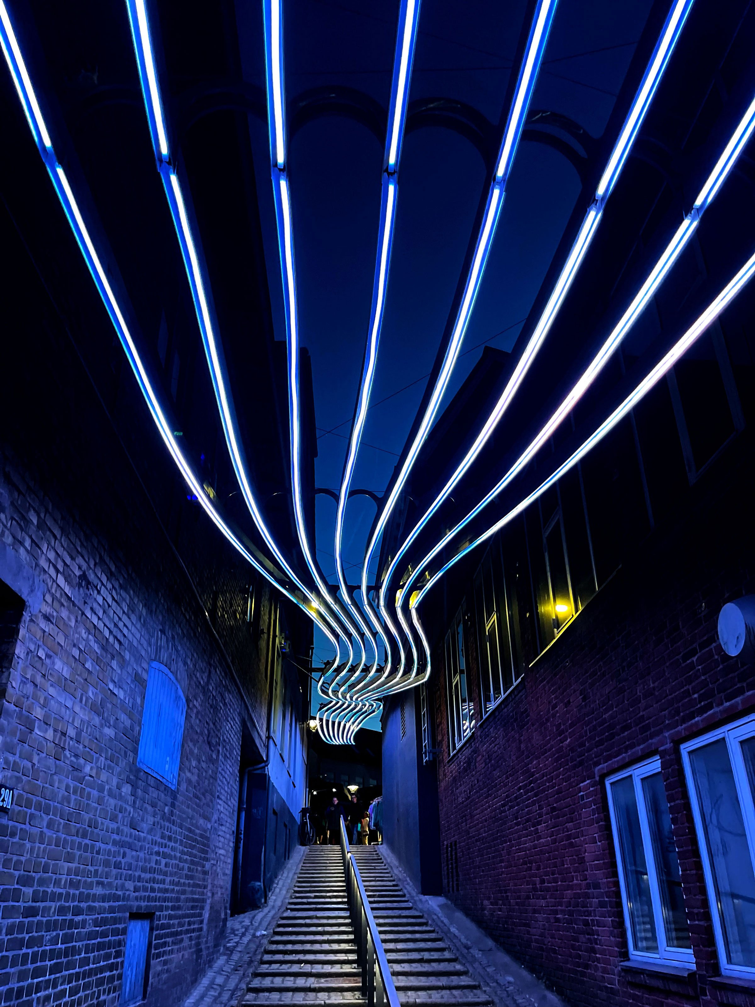 Under Oskar Kolianders <i>Strømmen</i> bevæger man sig gennem en passage under et bølgende LED-loft. Værket forvandler rummet til en lysende strøm, der leder blikket og kroppen videre mod gågaden. Foto: Peter Bjerke