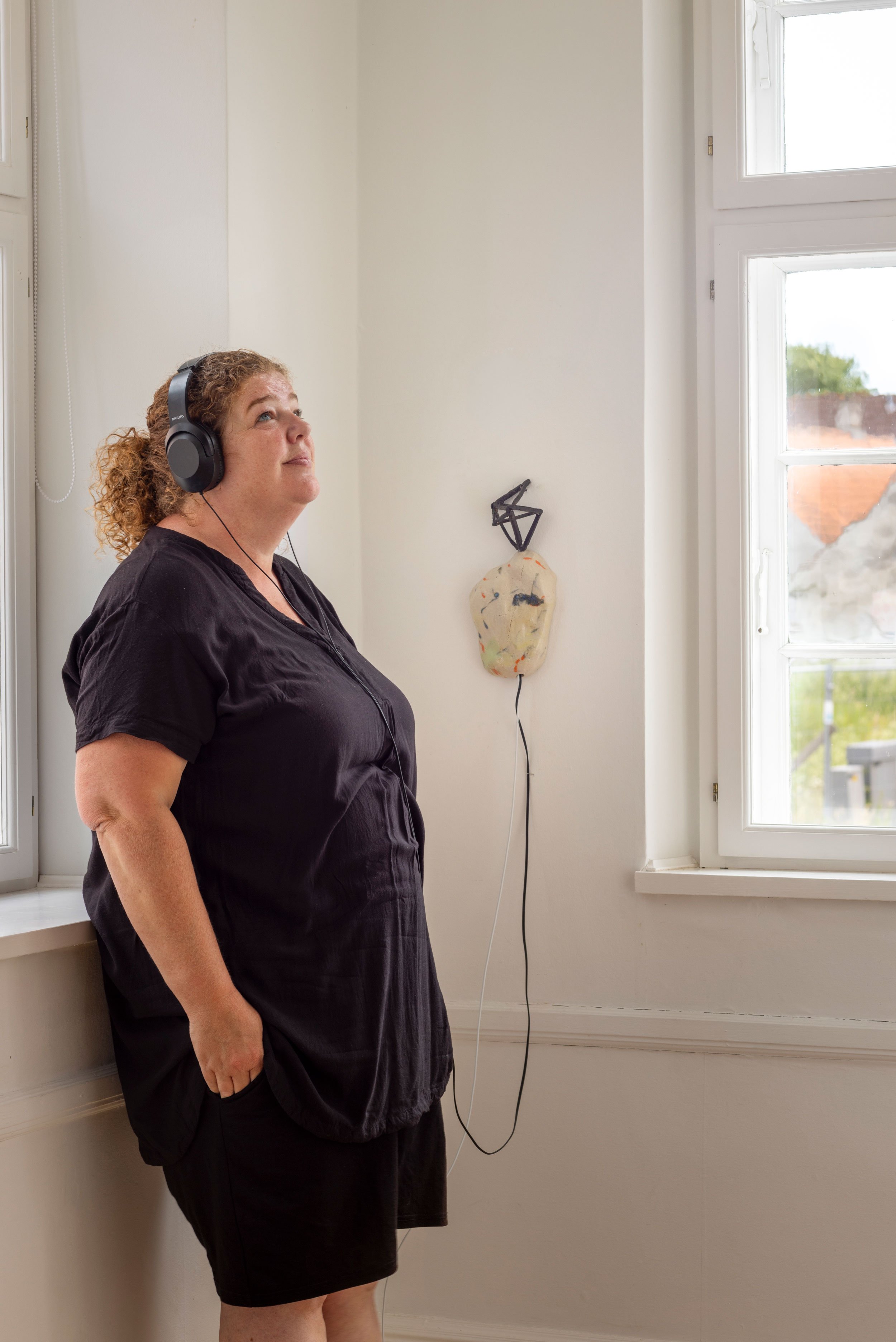 En gæst lytter til lydværket <i>Lenge før teknologien ble magi,</i> 2026. Foto: Jan Søndergaard.