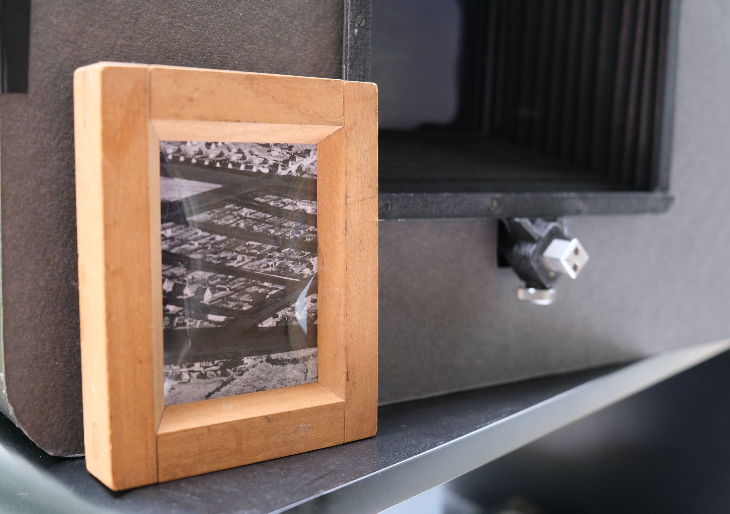 Installationsview, <i>I skiftende lys</i>, hOLME kUNSTHAL, 2026. Eksempel på en af de ældre kontaktrammer med luftfotos fra Holme placeret oven på lysfølsomt fotografisk papir. Luftfotos venligst udlånt af Højbjerg Holme Lokalhistoriske Arkiv. Foto: Sille Juline Høgly Petersen og Ane Bonde Rolsted.